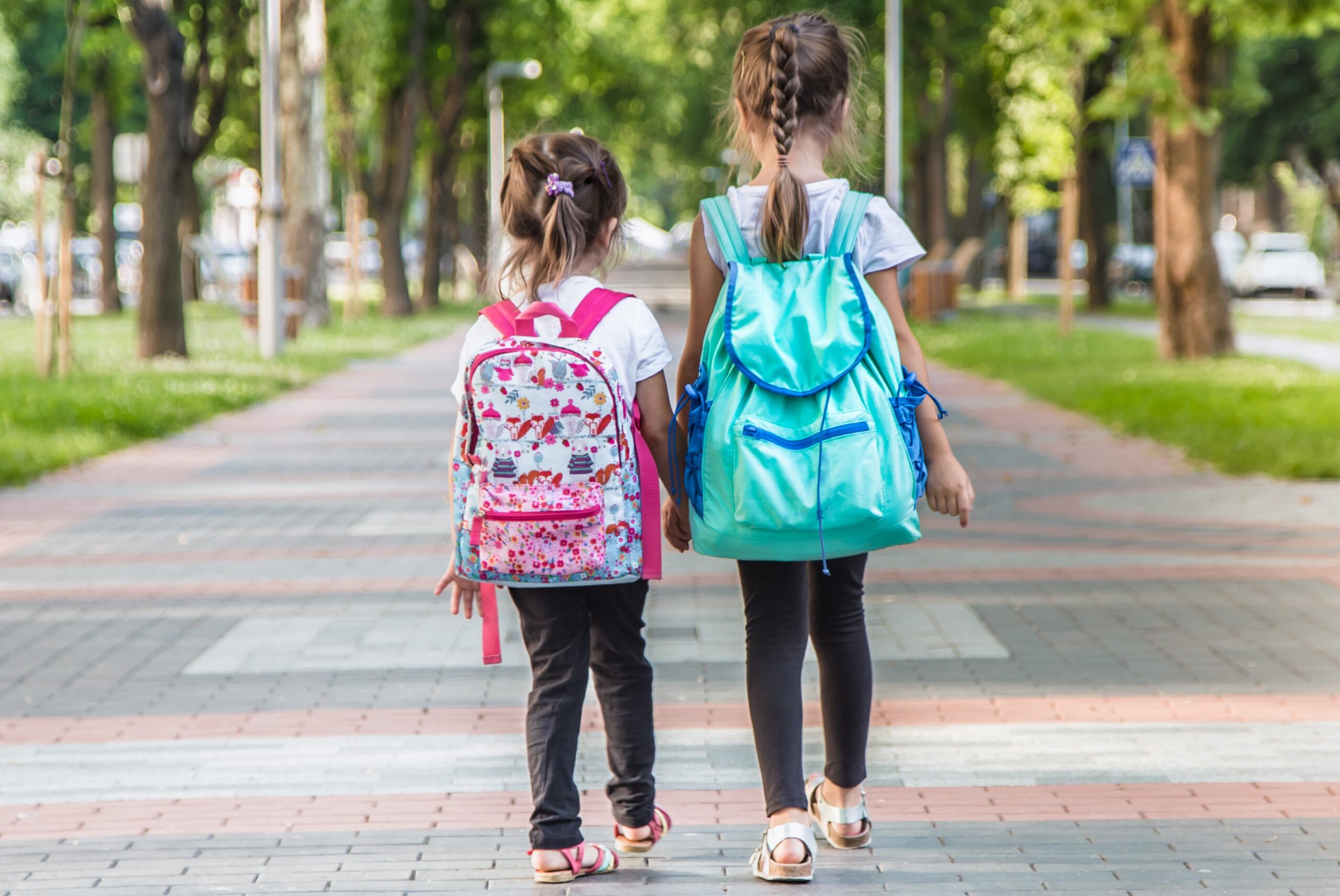 Back to school education concept with girl kids, elementary students, carrying backpacks going to class